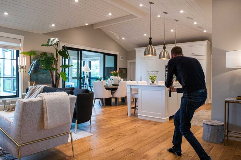 A couple reviews a three-dimensional home tour on a laptop beside printed floor plans.
